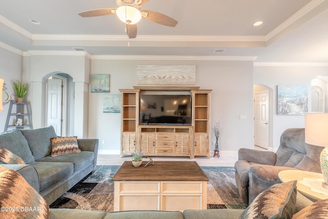 living room featuring a tray ceiling, ornamental molding, ceiling fan, and hardwood / wood-style flooring