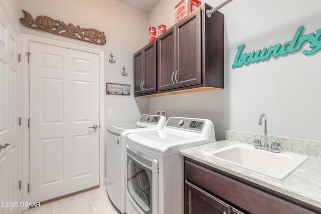 washroom with cabinets, separate washer and dryer, sink, and light hardwood / wood-style flooring