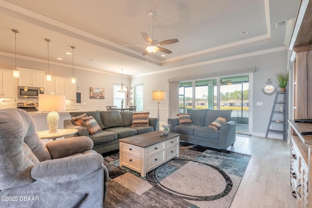 living room with a raised ceiling, a healthy amount of sunlight, and light hardwood / wood-style floors