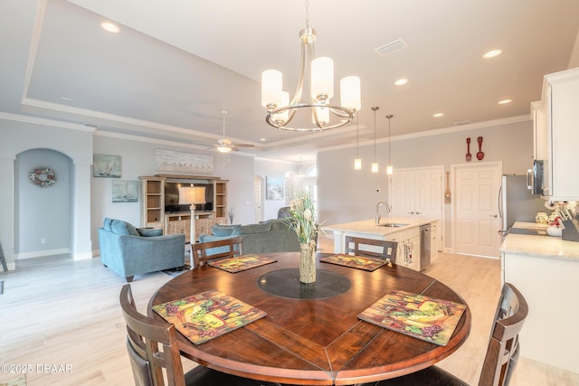 dining room featuring sink, ceiling fan with notable chandelier, ornamental molding, and light wood-type flooring