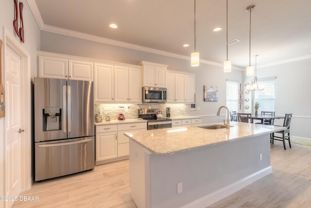 kitchen with sink, light stone counters, appliances with stainless steel finishes, a kitchen island with sink, and white cabinets