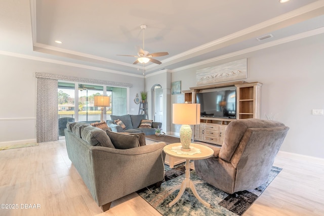 living room with crown molding, light hardwood / wood-style floors, a raised ceiling, and ceiling fan