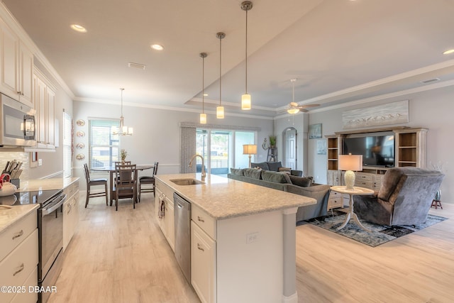 kitchen featuring sink, hanging light fixtures, a raised ceiling, stainless steel appliances, and a kitchen island with sink