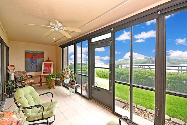 sunroom with ceiling fan, plenty of natural light, and a water view