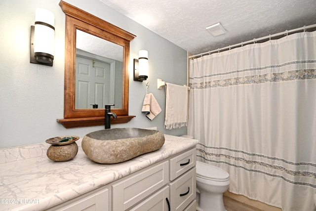 bathroom with vanity, a shower with curtain, a textured ceiling, and toilet