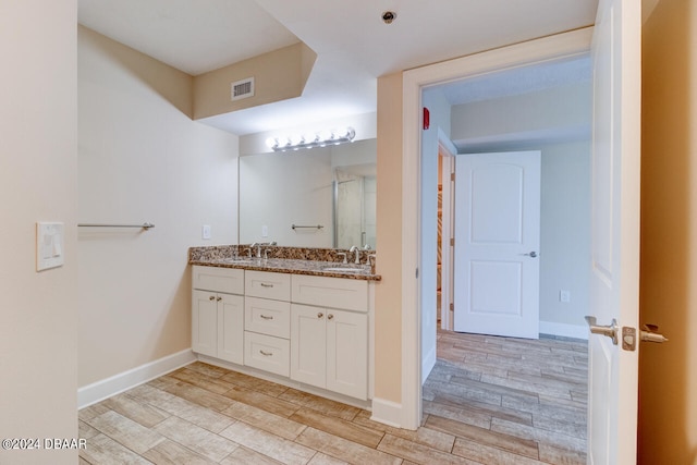 bathroom featuring double vanity, wood finished floors, visible vents, and a sink