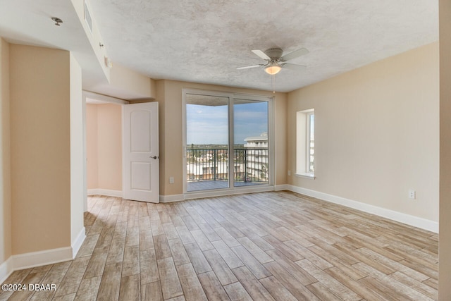unfurnished room featuring a ceiling fan, visible vents, baseboards, a textured ceiling, and wood finished floors