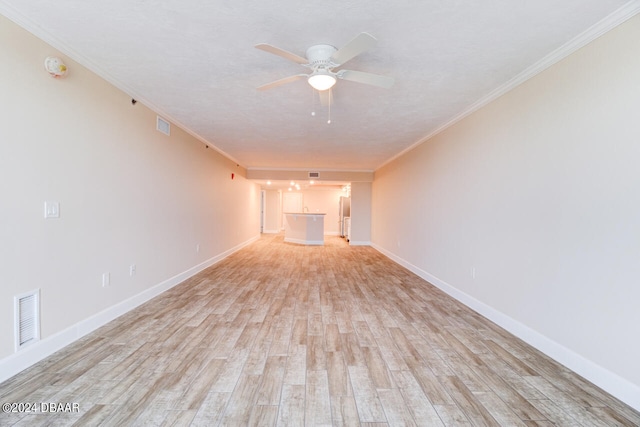 unfurnished living room with light wood-style floors, ornamental molding, baseboards, visible vents, and a ceiling fan