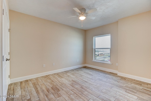 spare room with a ceiling fan, light wood-style flooring, and baseboards