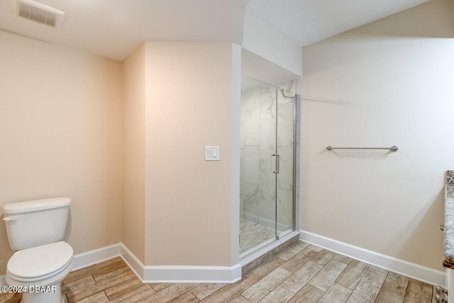 full bathroom featuring toilet, a marble finish shower, visible vents, baseboards, and wood finished floors