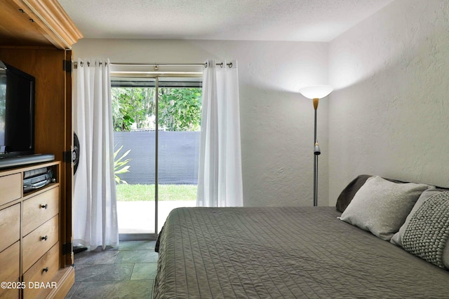 bedroom featuring a textured ceiling, multiple windows, and access to outside