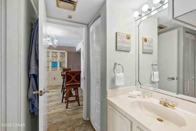 bathroom with a textured ceiling, a chandelier, and vanity