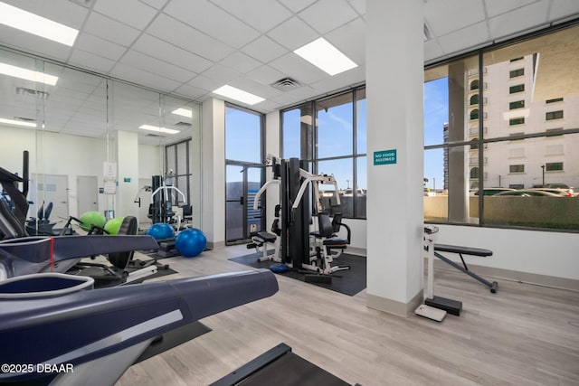 exercise room with a drop ceiling and wood-type flooring