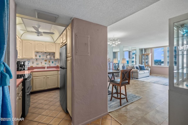 kitchen featuring black / electric stove, electric panel, stainless steel fridge, ceiling fan with notable chandelier, and sink