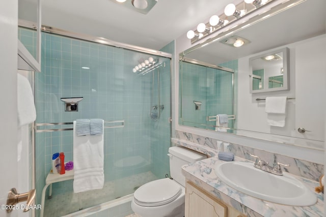 bathroom with a shower with door, vanity, and toilet