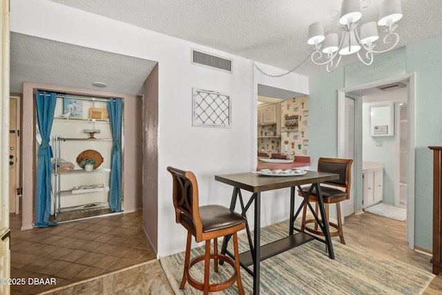 dining space with a textured ceiling, a notable chandelier, and dark tile patterned flooring