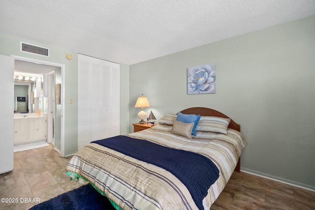 tiled bedroom with a closet, connected bathroom, and a textured ceiling