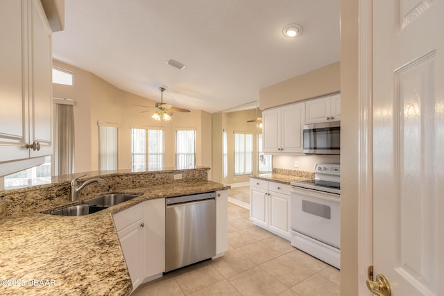 kitchen with appliances with stainless steel finishes, sink, white cabinetry, light stone counters, and lofted ceiling