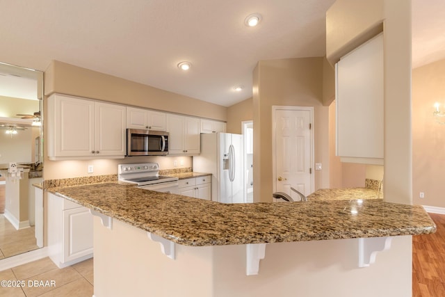 kitchen featuring white cabinetry, white appliances, kitchen peninsula, and a breakfast bar