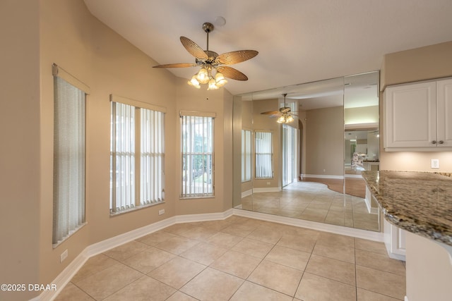 unfurnished dining area with ceiling fan, light tile patterned floors, and vaulted ceiling