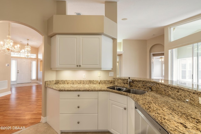 kitchen featuring sink, stainless steel dishwasher, white cabinetry, and light stone countertops