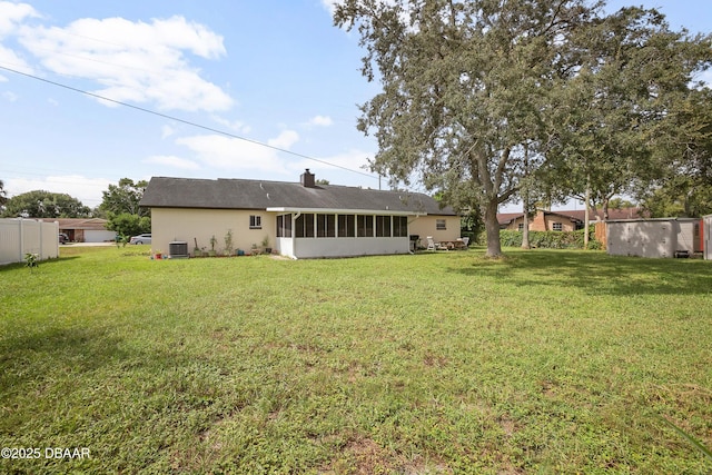 back of property with central AC, a yard, and a sunroom