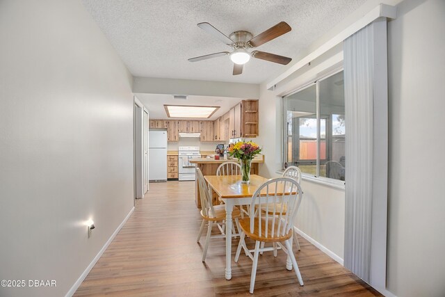 dining area with ceiling fan, light hardwood / wood-style floors, and a textured ceiling