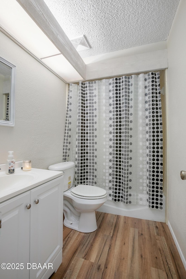 full bathroom featuring shower / tub combo, vanity, wood-type flooring, a textured ceiling, and toilet