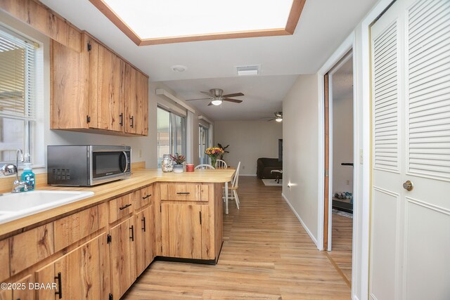 kitchen with ceiling fan, light hardwood / wood-style floors, and kitchen peninsula