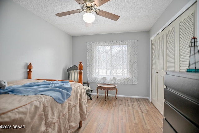 bedroom with ceiling fan, light hardwood / wood-style flooring, a closet, and a textured ceiling