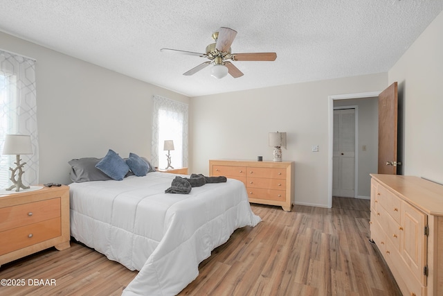 bedroom featuring ceiling fan, light hardwood / wood-style floors, and a textured ceiling