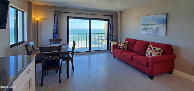 tiled living room featuring a water view and a textured ceiling