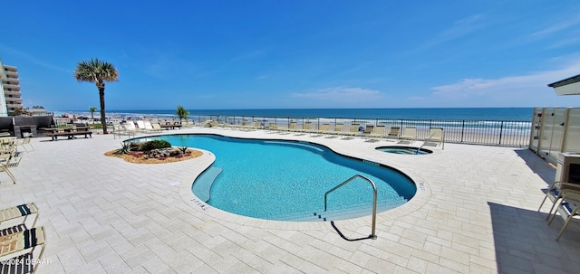 view of pool featuring a water view, a patio, and a hot tub