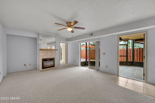 unfurnished living room featuring a textured ceiling, light carpet, ceiling fan, and a fireplace