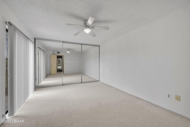 carpeted spare room featuring a textured ceiling and ceiling fan