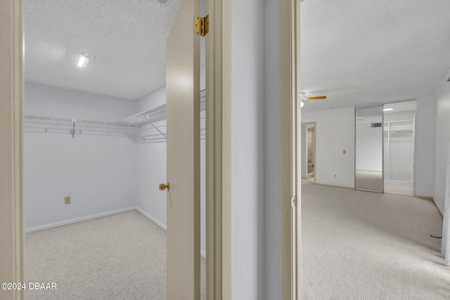 walk in closet with light colored carpet and ceiling fan