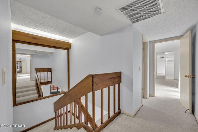 hall featuring a textured ceiling and light carpet