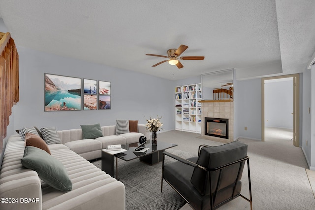 carpeted living room featuring ceiling fan, a tiled fireplace, and a textured ceiling