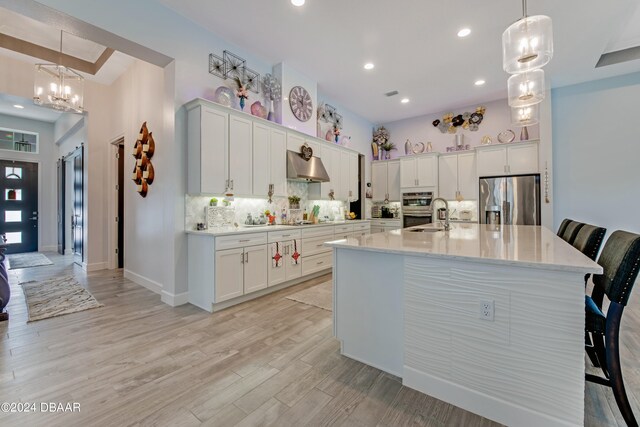 6232 W Fallsgrove Ln, Port Orange, FL 32128 - kitchen featuring white cabinets, a kitchen island with sink, light wood-type flooring, and appliances with stainless steel finishes