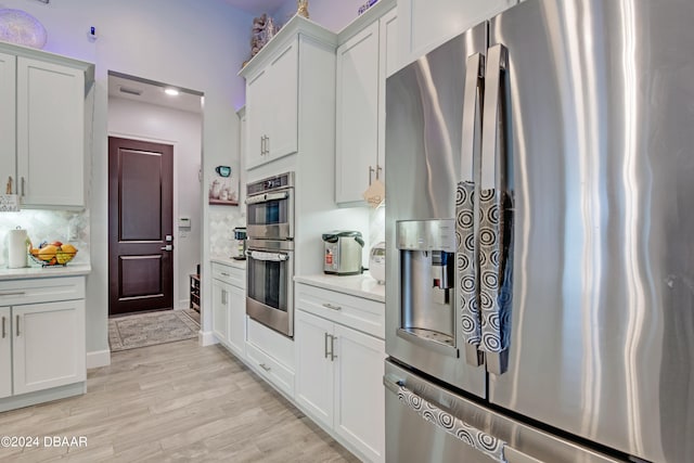 6232 W Fallsgrove Ln, Port Orange, FL 32128 - kitchen with light wood-type flooring, appliances with stainless steel finishes, backsplash, and white cabinets