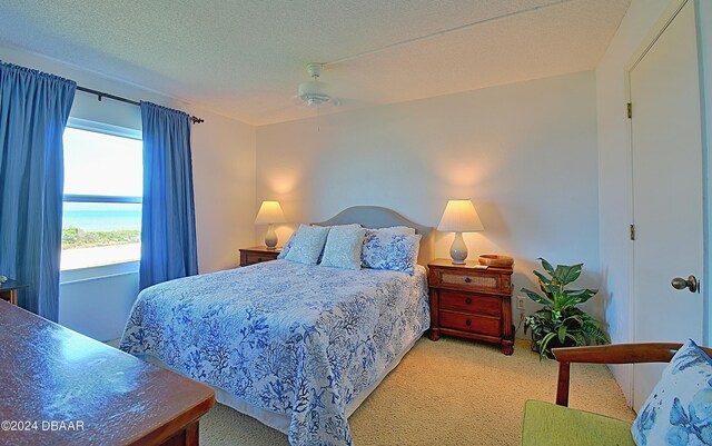 carpeted bedroom with a water view, a textured ceiling, and ceiling fan