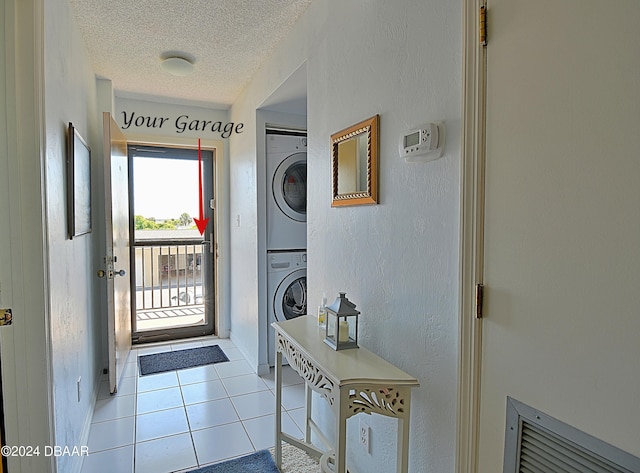 clothes washing area featuring stacked washer and dryer, a textured ceiling, and light tile patterned floors