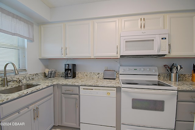 kitchen featuring white cabinetry, light stone countertops, white appliances, and sink