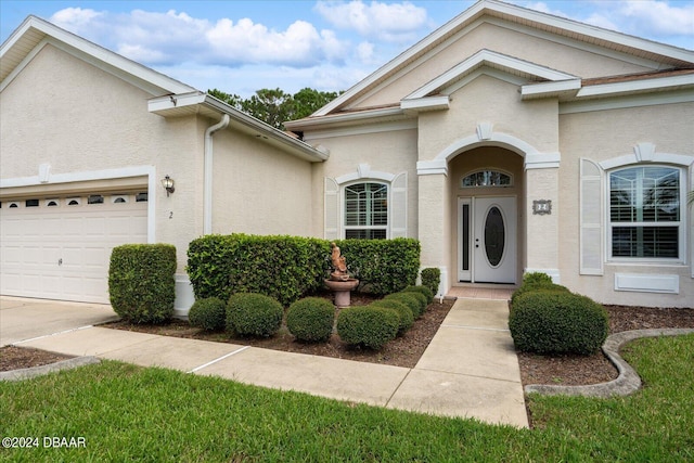 2 Elliot Pl, Palm Coast, FL 32164 - view of exterior entry with stucco siding, an attached garage, and concrete driveway