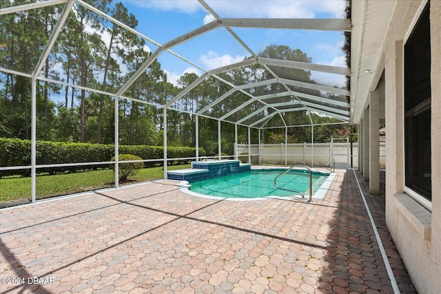 view of pool with glass enclosure, an in ground hot tub, and a patio