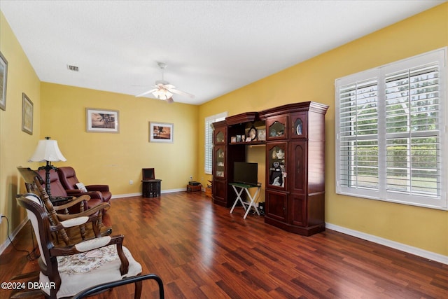 living area with ceiling fan, dark hardwood / wood-style flooring, and a textured ceiling