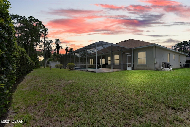 exterior space featuring central air condition unit, glass enclosure, a yard, and a patio