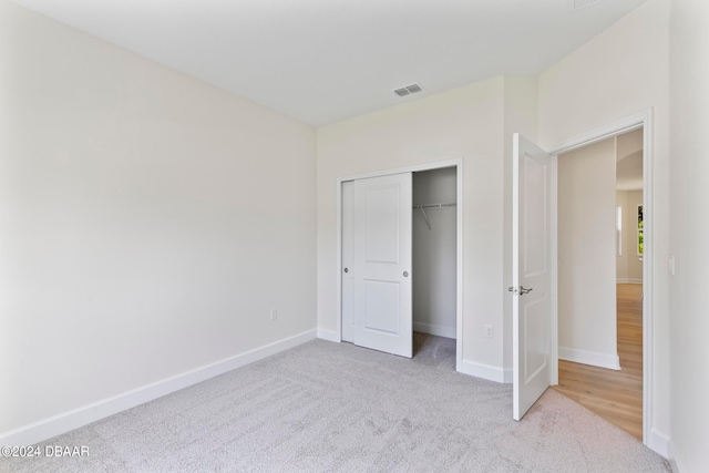 unfurnished bedroom featuring a closet and light colored carpet