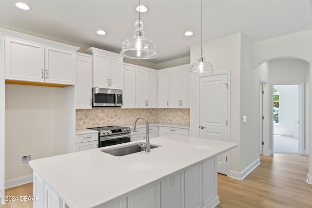 kitchen with white cabinetry, appliances with stainless steel finishes, light wood-type flooring, sink, and an island with sink