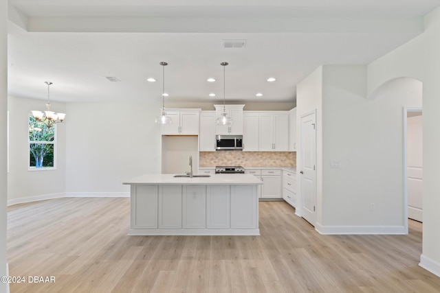 kitchen with light hardwood / wood-style floors, white cabinetry, sink, appliances with stainless steel finishes, and a kitchen island with sink